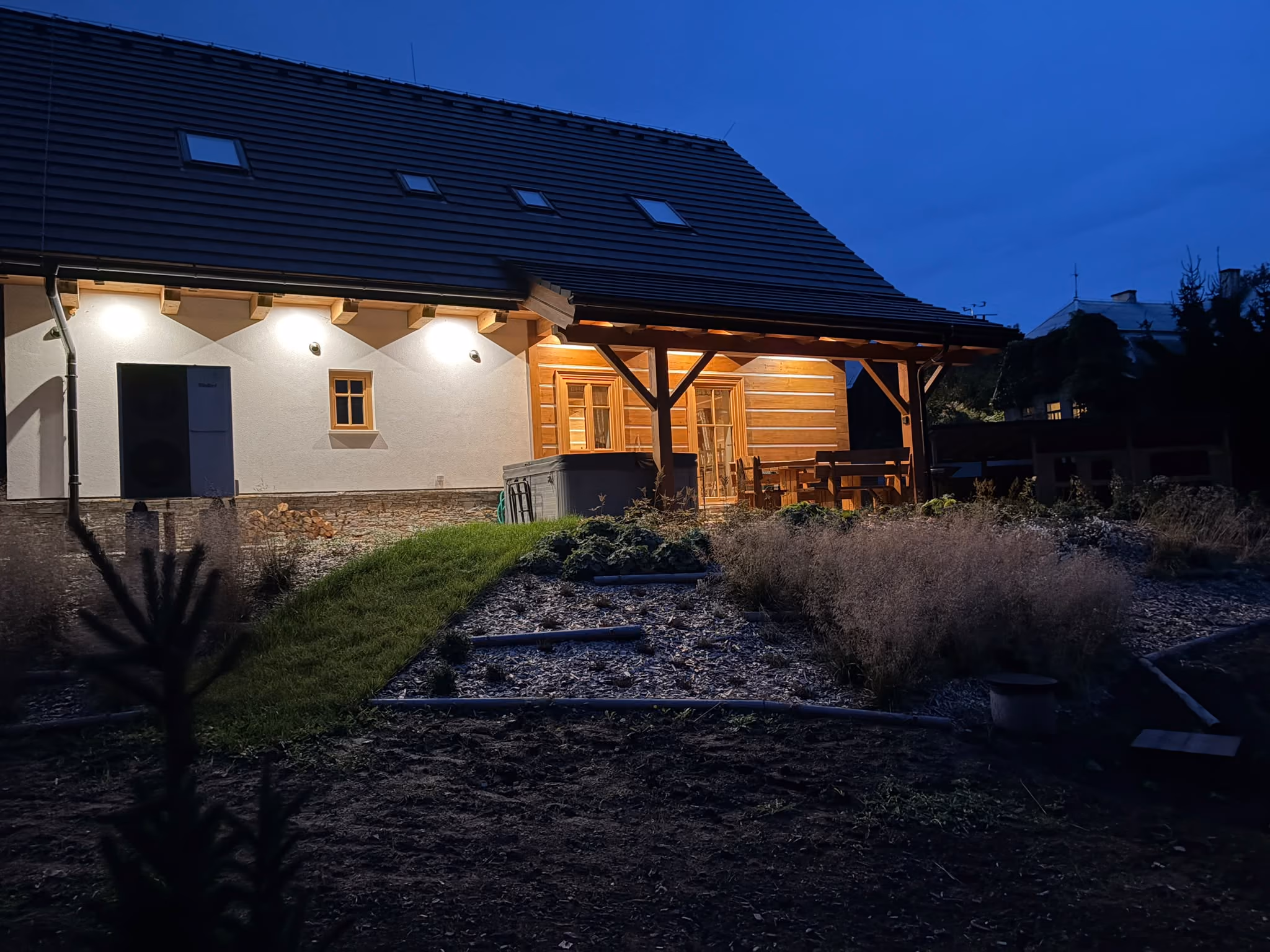Zahrada a omítnutá strana roubenky večer